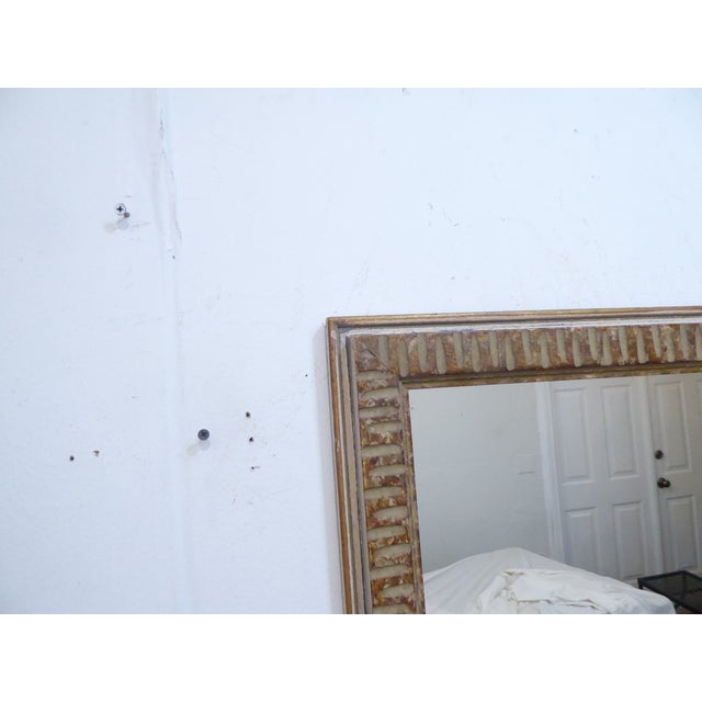 This modernist carved wood mirror has a weathered finish with traces of gold and measures 28.5"H x 25.25"W.