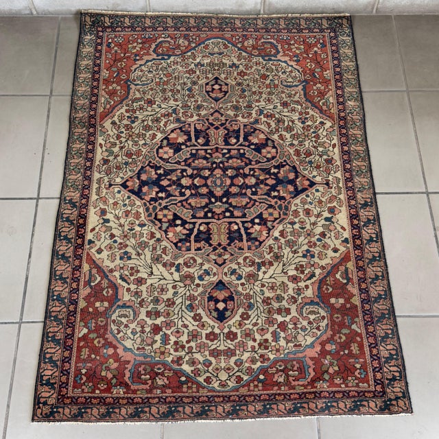 A precious and charming vintage rug with a light background, attributed to the renowned 19th-century Persian Sarouk...