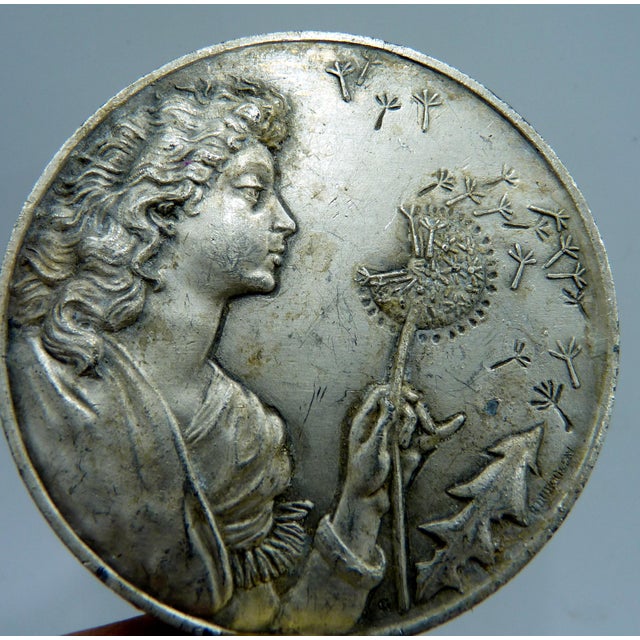 French commemorative Larousse medallion depicting an Art Nouveau-inspired allegorical female figure releasing dandelion...
