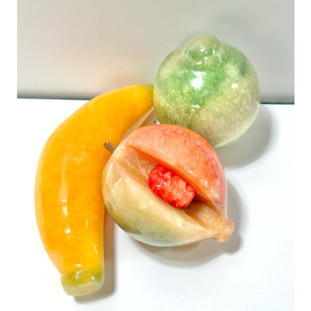 A charming set of hand-carved stone fruit sculptures including a banana, peach, and pear. Each piece is carved from...
