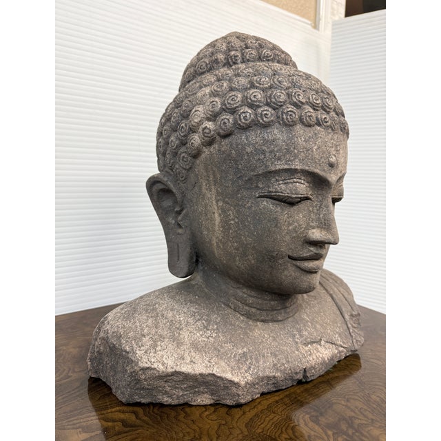 Design Plus Gallery presents a Buddha Bust of Hand-Carved Lava Stone from Indonesia. The top of the Enlightens head are...