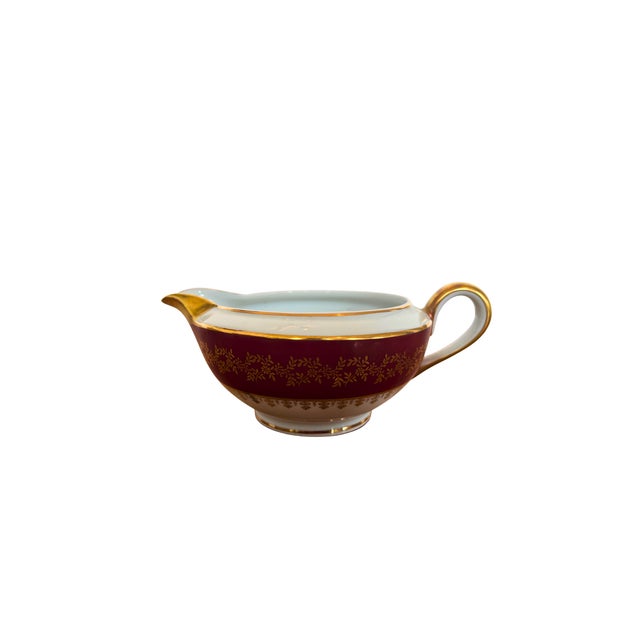 A striking Limoges porcelain dinner service, dressed in a rich ruby red border delicately adorned with fine hand-applied...