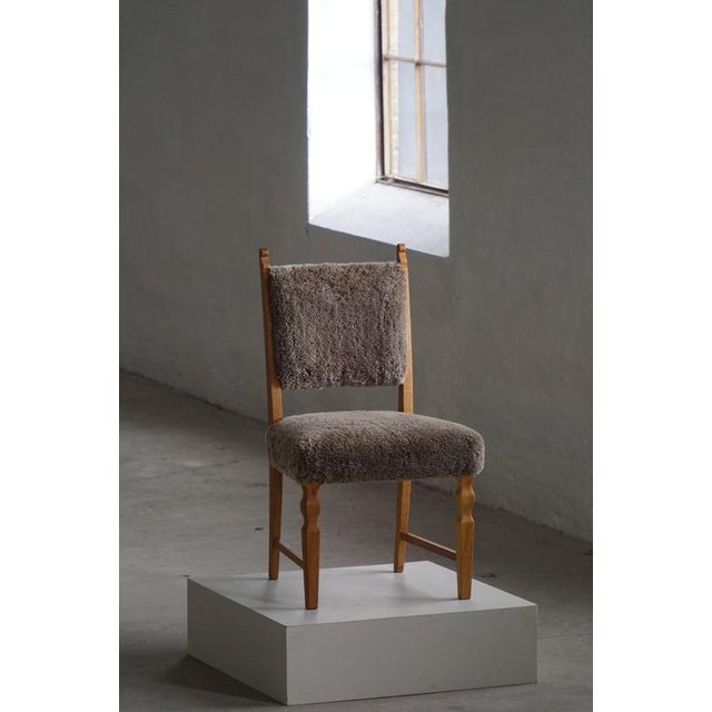 A beautiful set of 6 Danish chairs, showcasing carved oak legs and reupholstered seats and backs in a quality shearling...