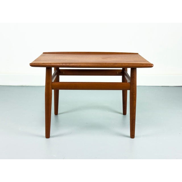 Organically designed teak side table. The distinctive features include the raised edge on the sides and the elegant frame...