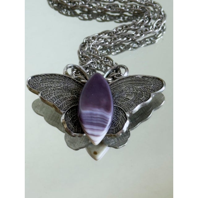 Vintage statement pendant necklace featuring a large silver tone butterfly suspended from a substantial opera length...