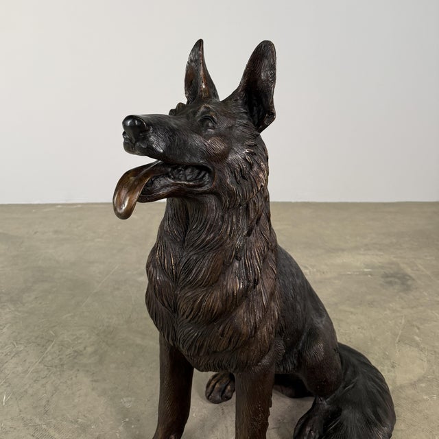A beautifully rendered bronze sculpture of a seated German Shepherd, captured in a relaxed and attentive posture with its...