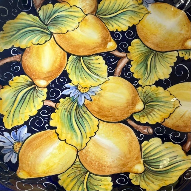 Italian ceramic decorative shallow bowl / footed plate features a vibrant hand painted interior with lemons, flowers, and...