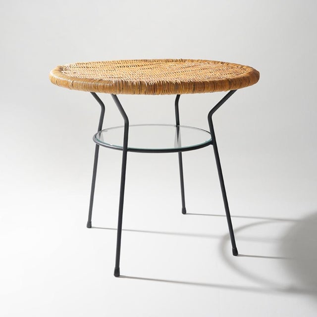A round rattan and metal side table from the 1950s, a design that brings together the visual lightness of its structure...