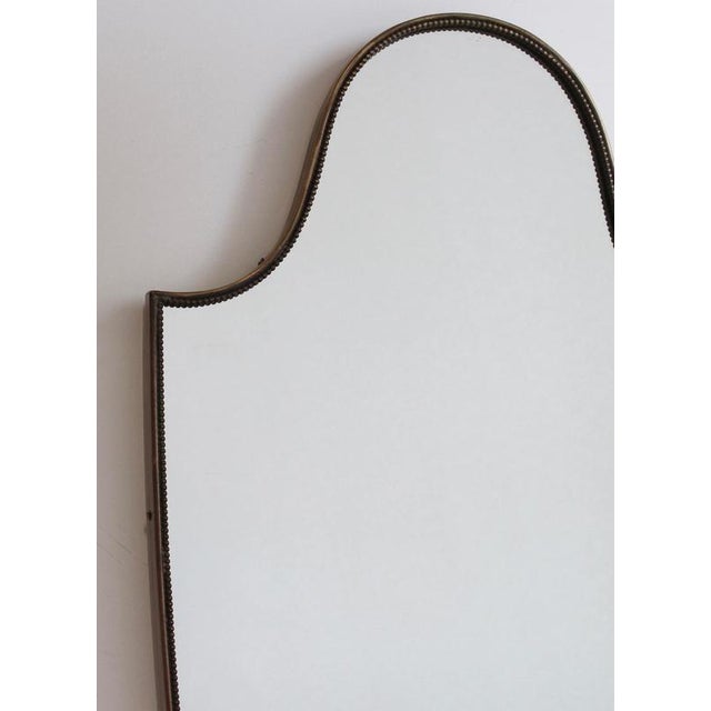 Mid-century italian wall mirror with brass frame and beading (circa 1960s). The mirror is classically-shaped and...