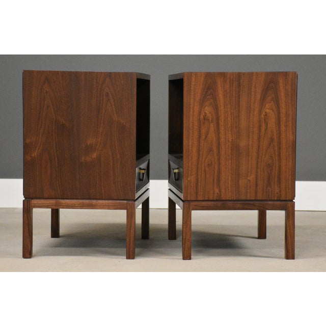 A pair of mid century modern walnut single drawer nightstands with rosewood drawer pulls and brass accents designed by...