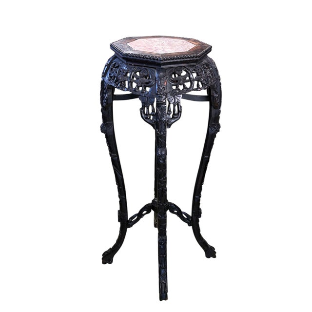 A 19th-century Chinese pedestal table featuring hand-carved rosewood with elaborate floral details and a marble top....