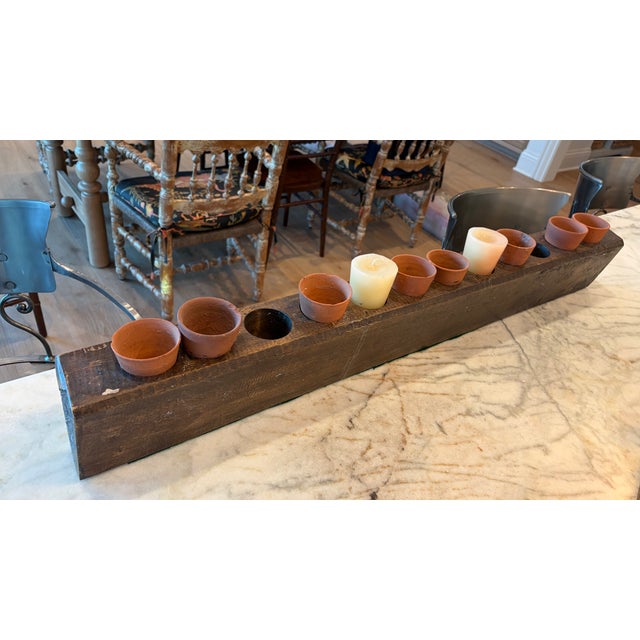 A substantial antique wooden sugar mold featuring twelve cylindrical cavities, beautifully aged with a rich, timeworn...