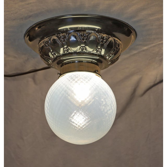 Art Nouveau ceiling lamp, circa 1915. Gometrically embossed brass. Original glass shade with a delicate blue tint. The...