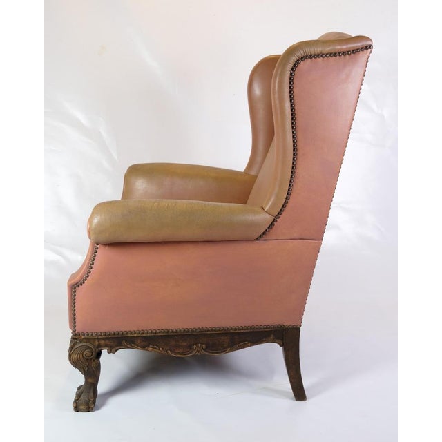 This antique Chesterfield-style high flap chair is a masterpiece of furniture art from the 1920s. Upholstered in brown...