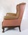 This antique Chesterfield-style high flap chair is a masterpiece of furniture art from the 1920s. Upholstered in brown...