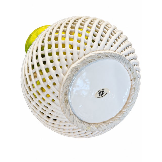 Made in Spain, this ceramic centerpiece features a stacked arrangement of yellow fruit with green accents in a white...
