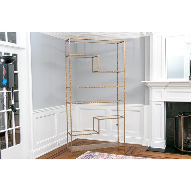 A majestic hammered wrought iron etagere with a beautiful gilt finish and eight 1/4” thick glass shelves. This high...