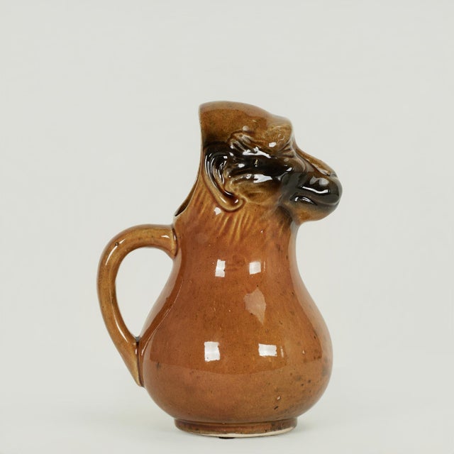 Whimsical antique glazed earthenware pitcher in the form of a smiling monkey. Marked Made in England on the bottom.