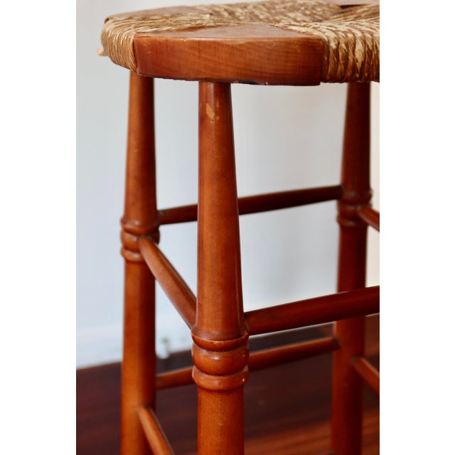 High bar stools in solid wood, featuring a woven straw seat and turned legs reminiscent of traditional craftsmanship. The...