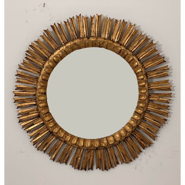 A beautiful French gilt sunburst (or starburst) mirror with gilded rays arranged around a mirror plate glass center....
