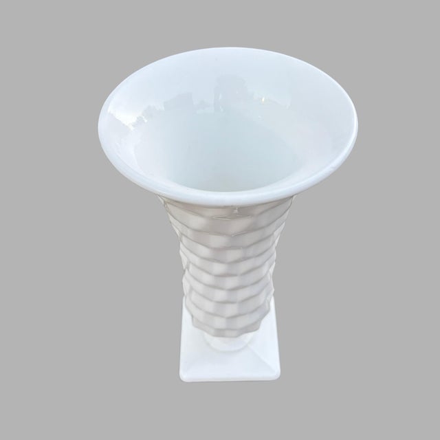 This is a milk glass vace made by Fostoria in their American pattern. Standing at 9.75” tall, with a 3.5” square base, it...
