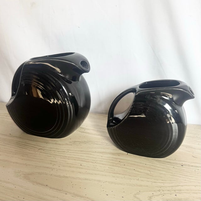This striking vintage set of two Art Deco disk pitchers exemplifies the bold sculptural spirit of early American...