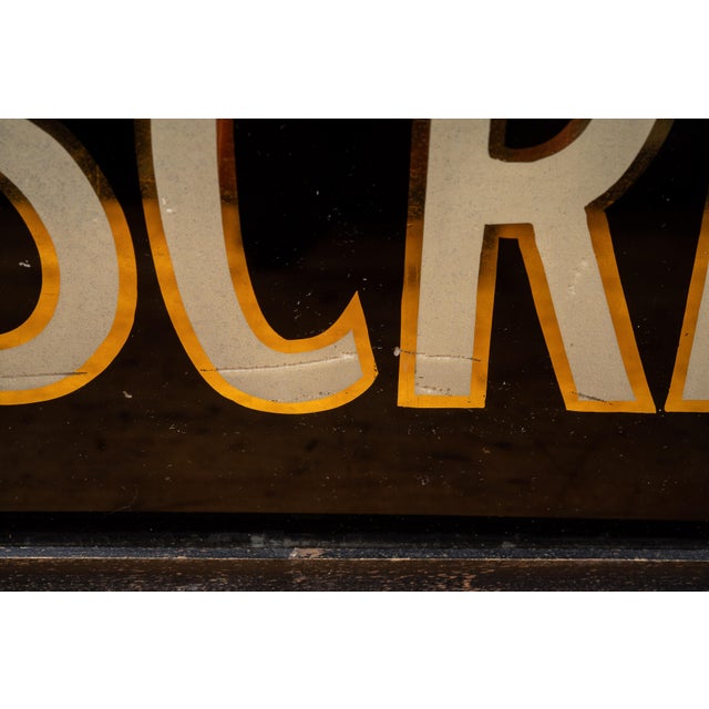Early 20th-century pharmacy sign featuring reverse-painted "PRESCRIPTIONS" lettering in cream with gilt shadow detailing...
