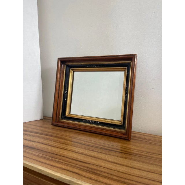 Walnut Toned wood Mirror with painted black and gilt accents. Motif accents each side of the frame. Slight Patina to the...