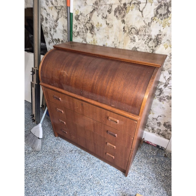 Elegant Danish secretary desk crafted in teak, featuring a roll-top design with a sleek, streamlined silhouette. The piece...