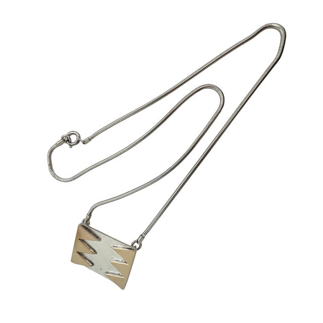 A rectangular sterling silver pendant by M&J Savitt is set off by applied 14-karat yellow gold triangles that run along...