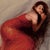 This oil painting features a figure draped in a flowing crimson gown, blending seamlessly with the soft, muted background....