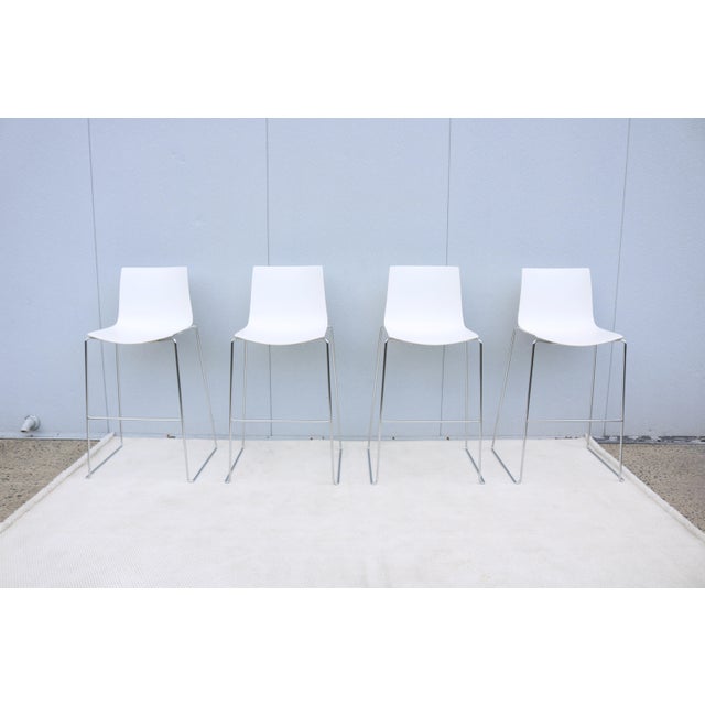 Fabulous set of four white stackable Catifa 46 bar stools with chromed steel sled bases, designed by the acclaimed studio...