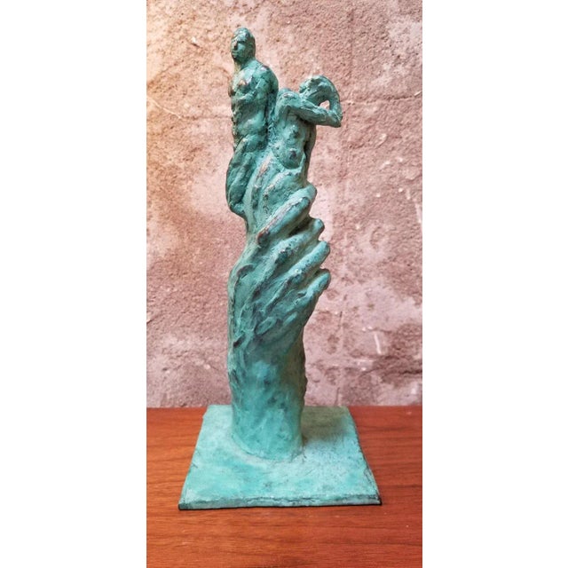 A unique, solid cast bronze sculpture of a hand holding three figures. Signed by sculptor at base, name is undecipherable...