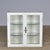 Metal display cabinet dating from circa 1930, featuring a white lacquered finish, two glass doors, and two glass shelves....
