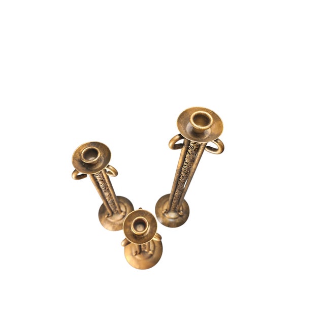 A striking vintage set of three graduated taper candlesticks featuring tall architectural silhouettes and intricate...