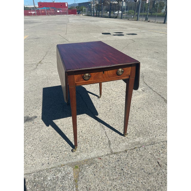 This is a stunning antique Pembroke drop-leaf end table, exhibiting classic Federal or Sheraton design characteristics....