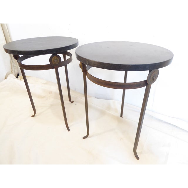 This pair of 24"H side tables have iron bases with a bronze finish and lion head medallions with marbleized wooden tops.