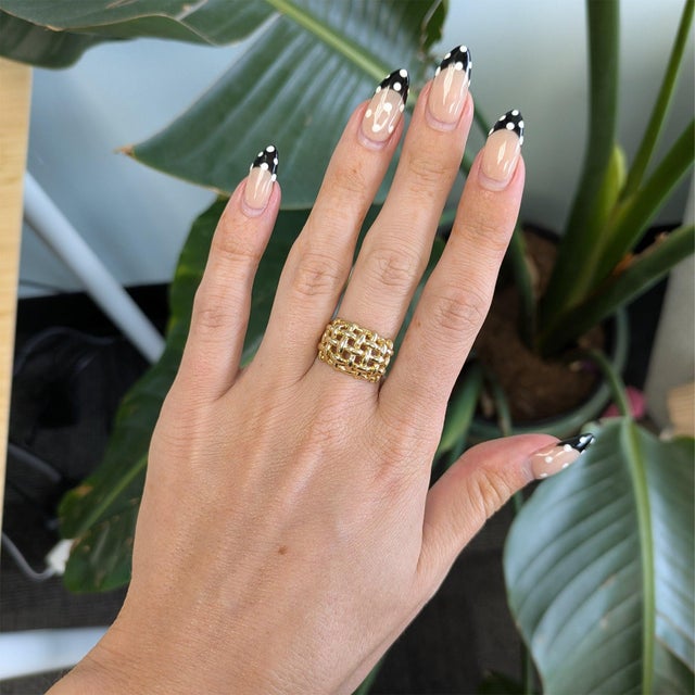 An intricately woven basket-weave design gives this solid 14K yellow gold estate ring texture and depth, catching the...