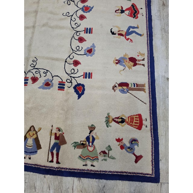 Vintage hand-loomed wool rug features a delightful European-inspired folk art design, showcasing colorful villagers,...