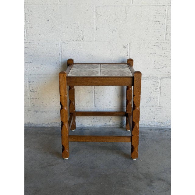 Turned legs support an inset ceramic tile surface in a compact, square frame. Raised post corners accentuate its sturdy...