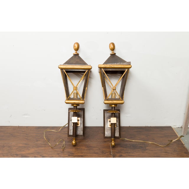 A pair of French gilt iron wall mounted lanterns from the mid 20th century, with single lights and acorn style finials....