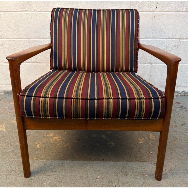 Mid-Century Modern wooden armchair showcases a classic Scandinavian design ethic featuring a sculptural wooden frame...