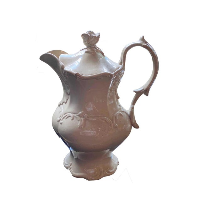 A nicely decorated English Drabware jug with scrolls and a rose top lid. The interior has a built in strainer. It looks as...