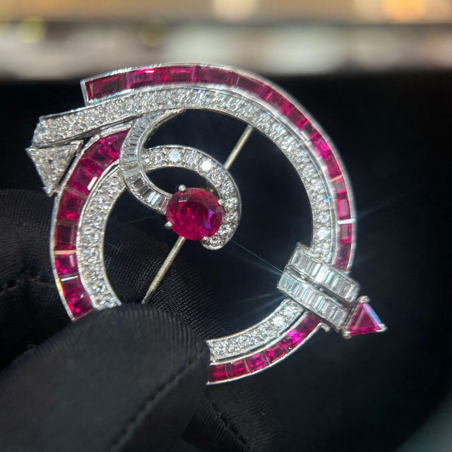 This exquisite Art Deco brooch features an AGL-certified natural no-heat ruby center stone surrounded by meticulously...