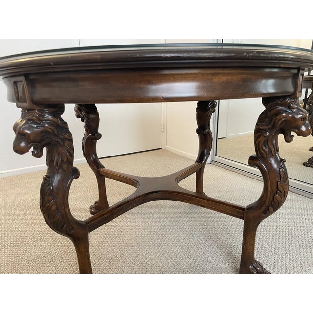 Stunning carved mahogany lion leg center table with glass top insert. Four dramatically carved legs each feature a fully...