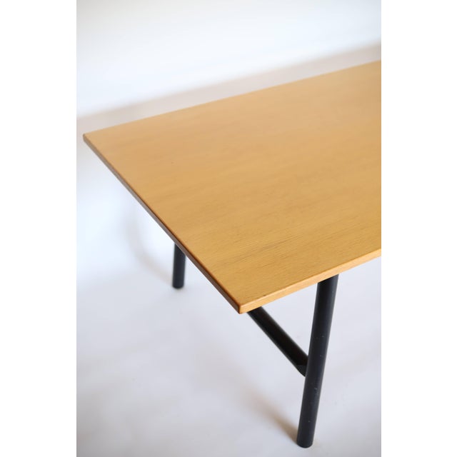 The Danish cabinetmaker dining table or desk features a light wood top and round black legs. The tabletop is crafted from...