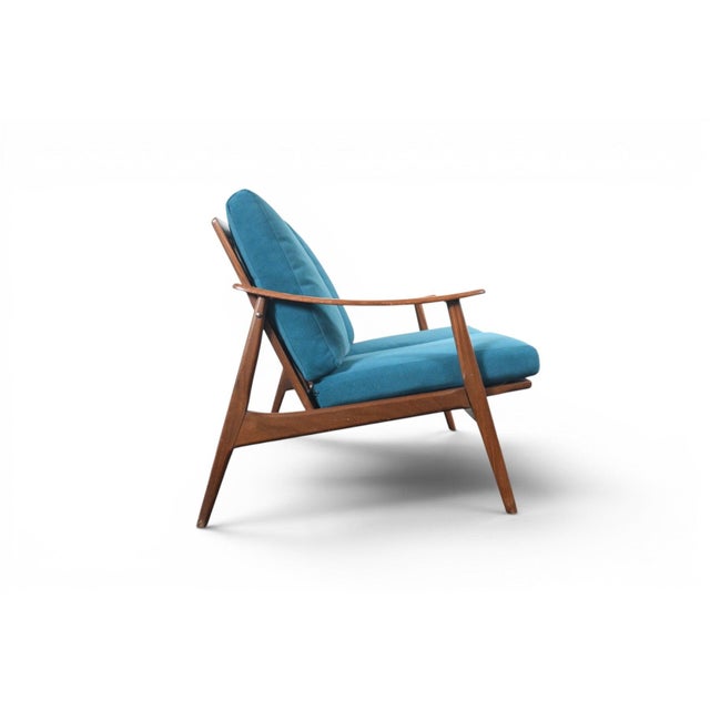 This teak-framed loveseat was made in Denmark in the 1960s, with the tapered lines and exposed wood frame typical of...
