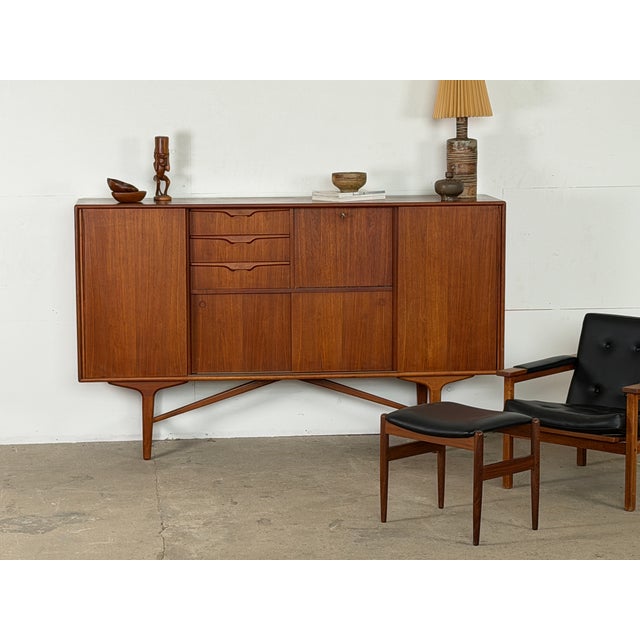 Mid-century sideboard in teak, dating from around the 1960s, with a long rectangular cabinet raised on sculpted legs...