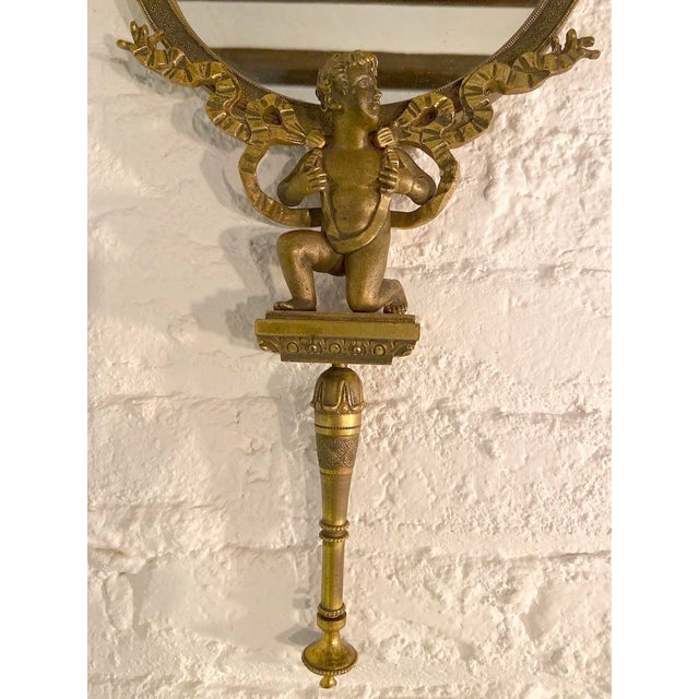 A rare and beautifully detailed 19th-century French vanity hand mirror, crafted in bronze with a warm gilded patina and...