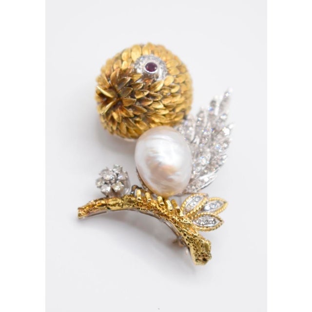 This is a vintage 18kt yellow and white gold diamond, baroque pearl, and ruby bird-motif brooch clip. It is complete with...